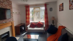 Een woonkamer met een televisie, bank en open haard.