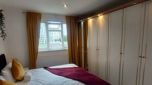 Een hotelkamer met een bed, een raam met gordijnen, een kledingkast en een radiator.