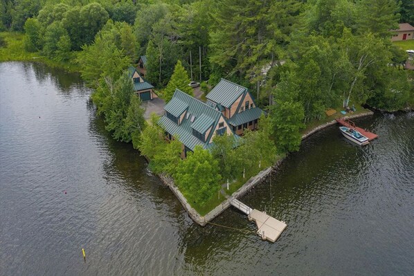 A lakeside cabin with a dock, surrounded by dense forest.