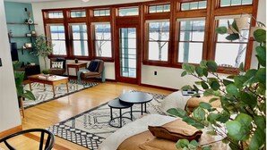 A spacious living room with a large window, a wooden floor, and a cozy seating area.