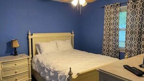 Un dormitorio con una cama individual, una mesita de noche, una lámpara y un ventilador de techo.