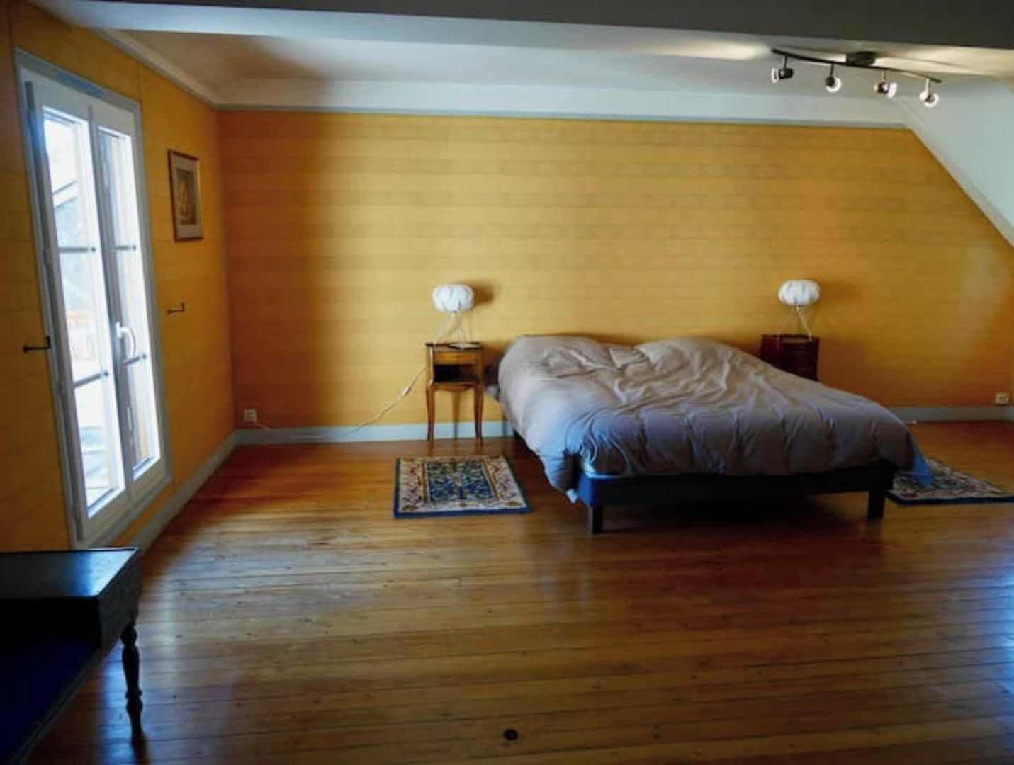 Une chambre à coucher avec un lit, deux tables de chevet, une fenêtre et une porte.