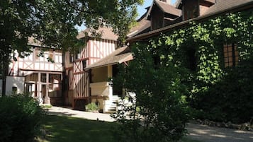 Una casa tradicional de entramado de madera con un jardín bien cuidado y un camino de entrada de grava.