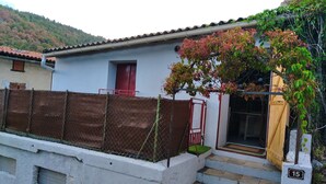 A residential building with a red door, a white exterior, and a small set of stone steps leading to a wooden door. - Maisonnette mountain view (Roquefeuil)