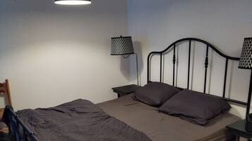Un lit simple avec un cadre en métal, une tête de lit et deux tables de chevet avec des lampes.
