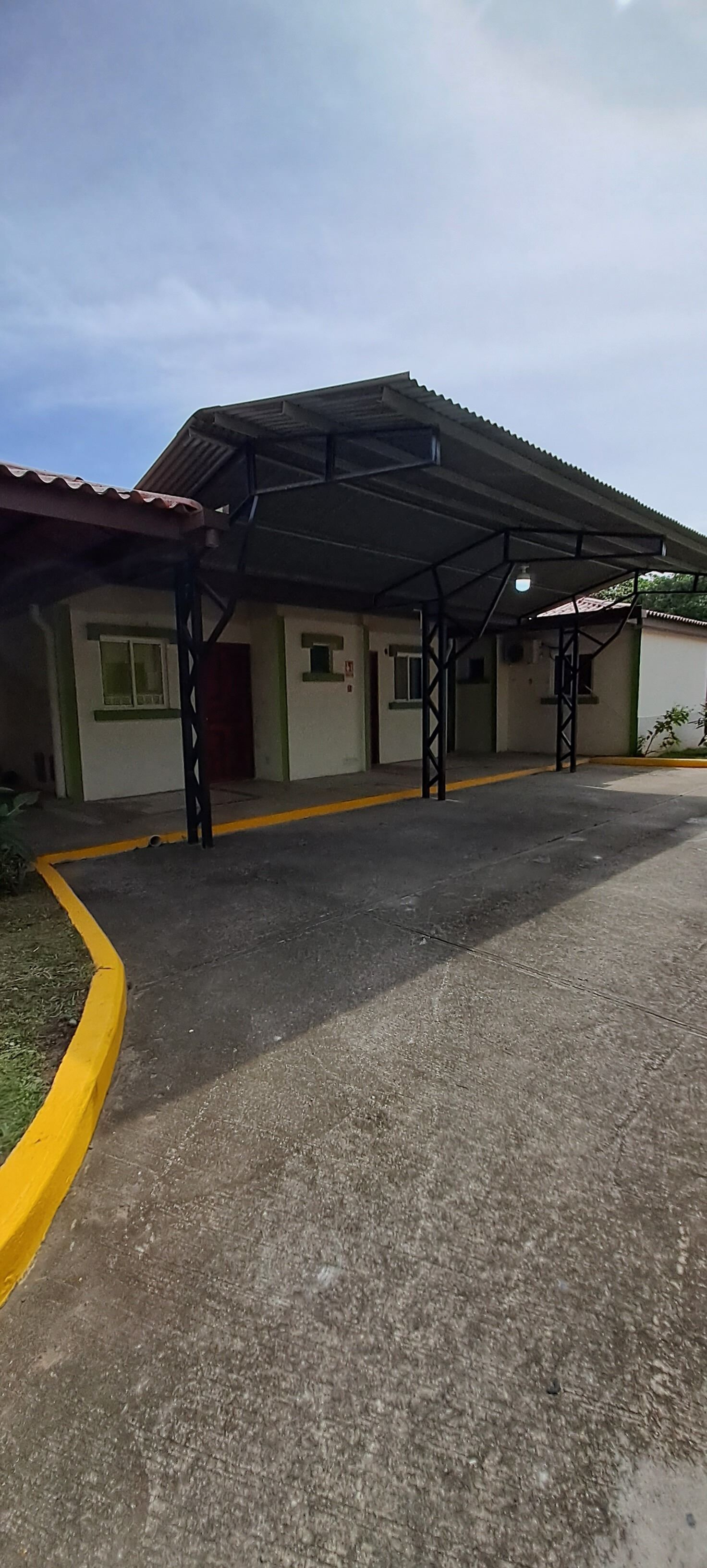 Un edificio con un acceso cubierto y un camino de entrada pavimentado.