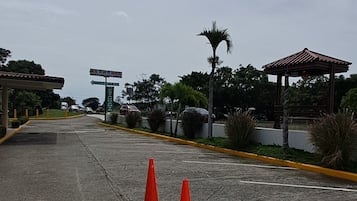 Un espacio para estacionar con dos conos de tráfico naranja, superficie pavimentada y una línea amarilla delimitando.