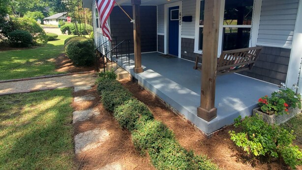 A residential house with a porch, an American flag, and a mailbox.