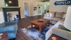 A living room with a fireplace, a sofa, a coffee table, and a TV mounted on the wall.