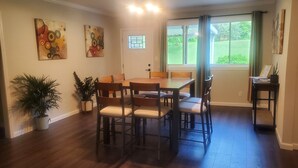 A dining area with a wooden table and chairs, potted plants, and artwork on the walls.