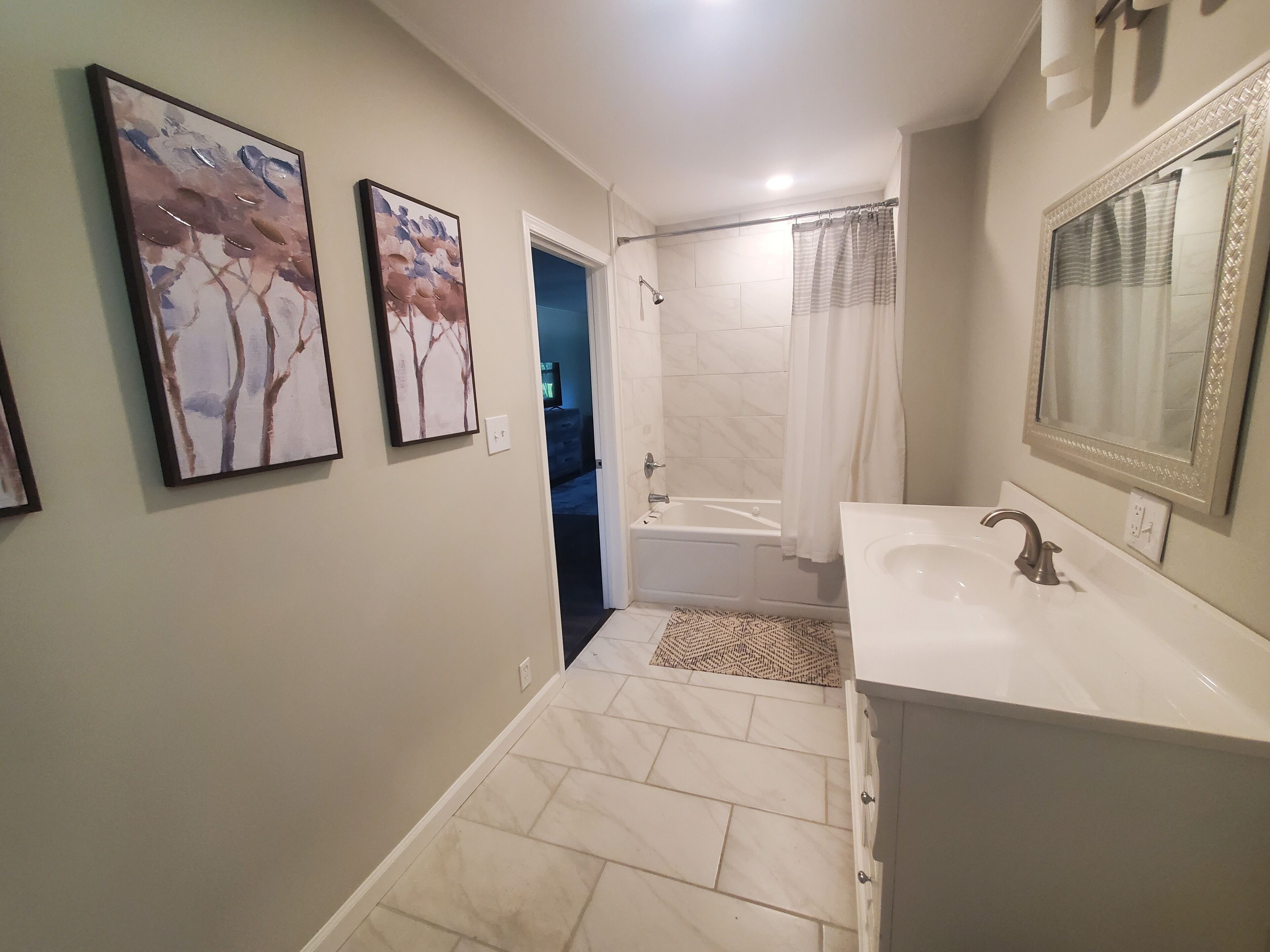 Een bad/douchecombinatie, een bubbelbad, een haardroger, handdoeken