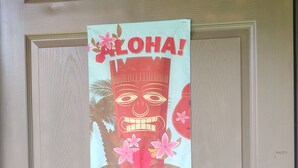 A door with a poster featuring a face and the word "ALOHA!"