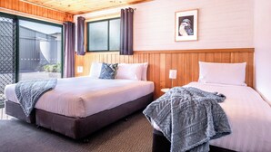 Ein Doppelzimmer mit zwei Betten, Holzbalkendecke und einem großen Fenster mit Vorhängen.