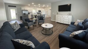 A modern living room with a dark blue sofa set, a coffee table, and a ceiling fan. - Historic Downtown Hermann Getaway-Walk to Wineries, Shops and Restaurants! (Hermann)