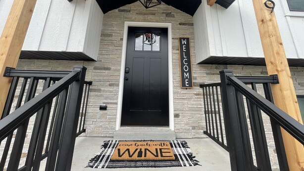 A black door with a welcome sign, a stone wall, and a wooden post with the number 139. - Historic Downtown Hermann Getaway-Walk to Wineries, Shops and Restaurants! (Hermann)
