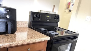 Una cocina con encimera de granito, estufa negra y armarios de madera.