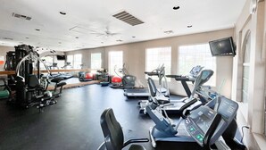 A gym with treadmills, elliptical machines, and exercise balls.