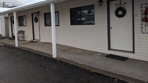 A single-story building with a porch, a door with a wreath, and a number '12' sign.