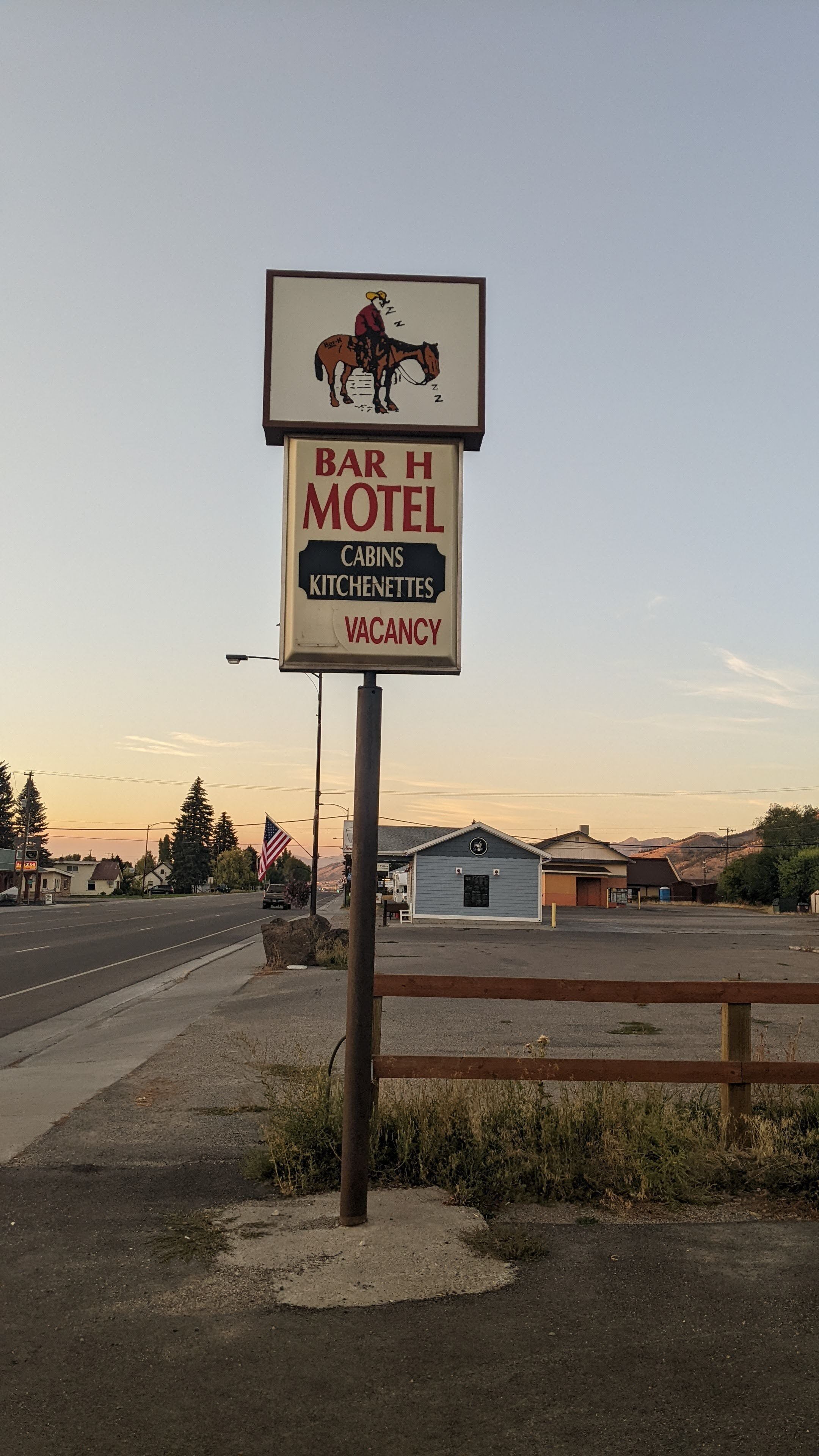 A motel sign with a horse and rider illustration, indicating a Bar H Motel with cabins and kitchenettes, and a vacancy.