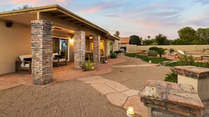 A covered patio area with stone pillars, outdoor seating, and a landscaped garden. - Sparkling Pool, Poker Table, and Relaxation at Sweetwater (Scottsdale)