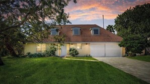 A two-story house with a garage, surrounded by a well-maintained lawn and trees. - Welcome to the Sunshine Shack in Corpus Christi! (Corpus Christi)