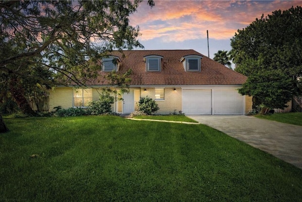A two-story house with a garage, surrounded by a well-maintained lawn and trees.