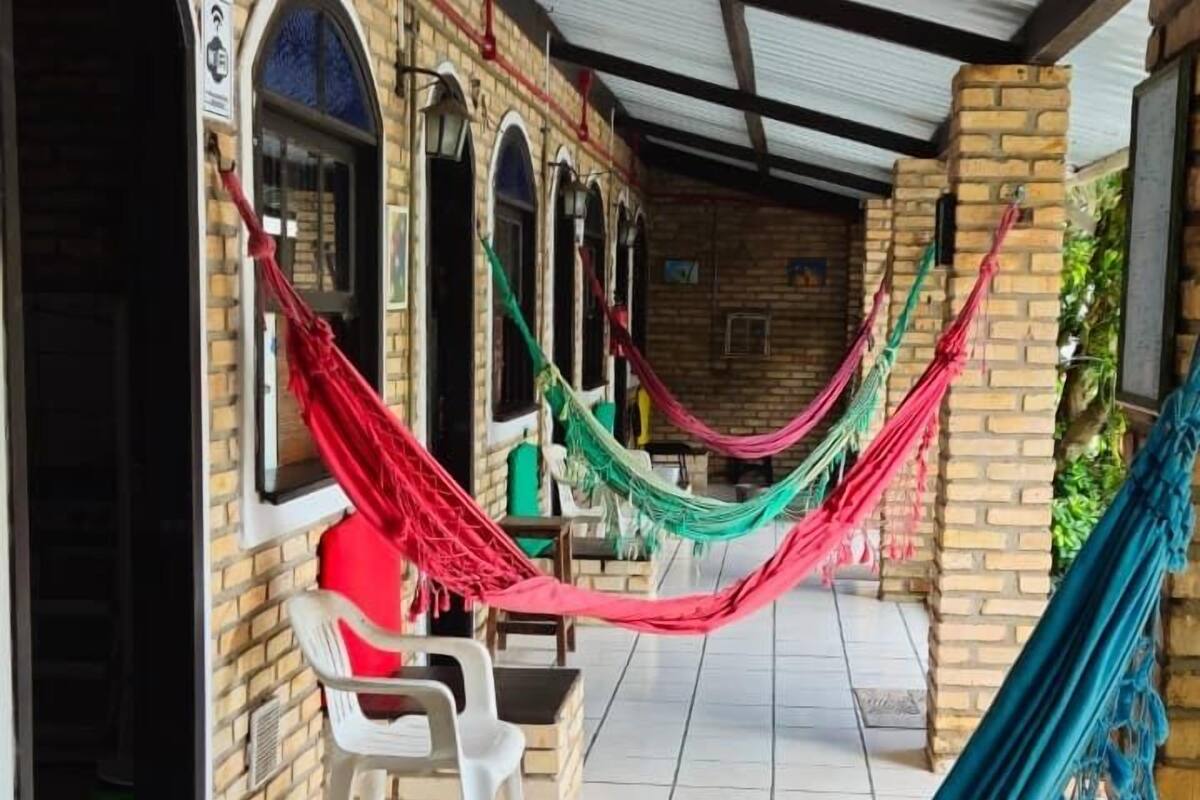 A covered outdoor area with a brick wall, tiled floor, and a hammock strung between two arches.