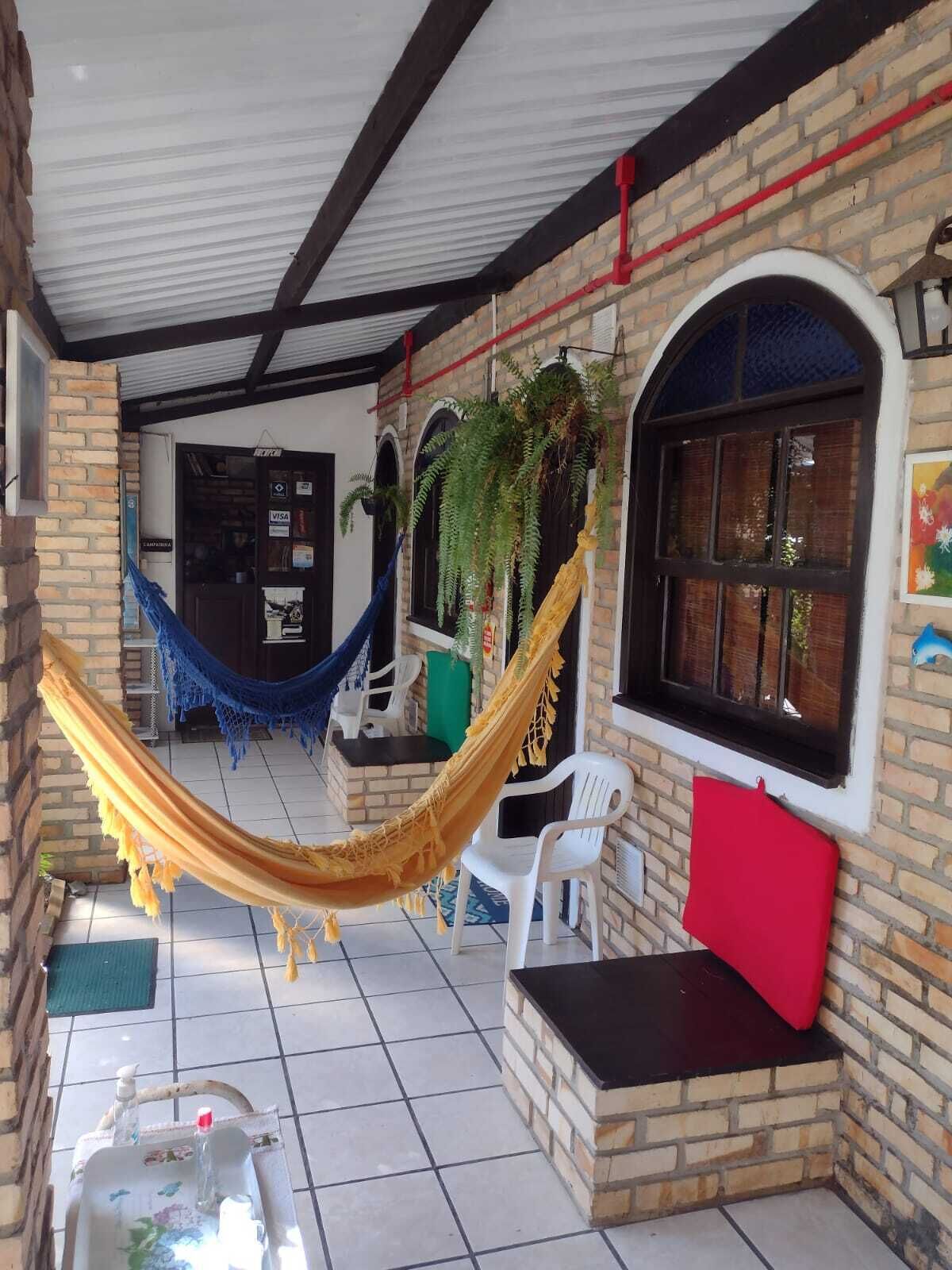 Un patio techado con una hamaca, mobiliario exterior y vistas a la calle.