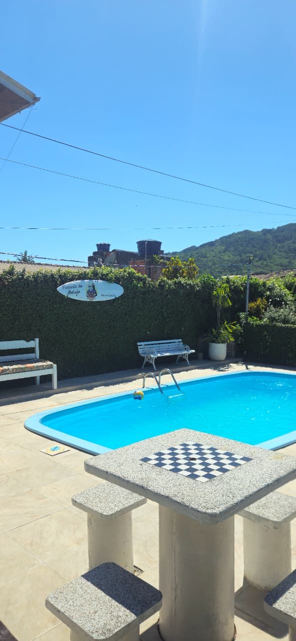 A swimming pool with a checkered pattern around the edge, a bench, and a table in the foreground.
