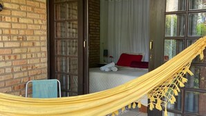 A room with a bed, a hammock, and a door leading to another room. - Pousada Pouso do Marujo (Florianópolis)
