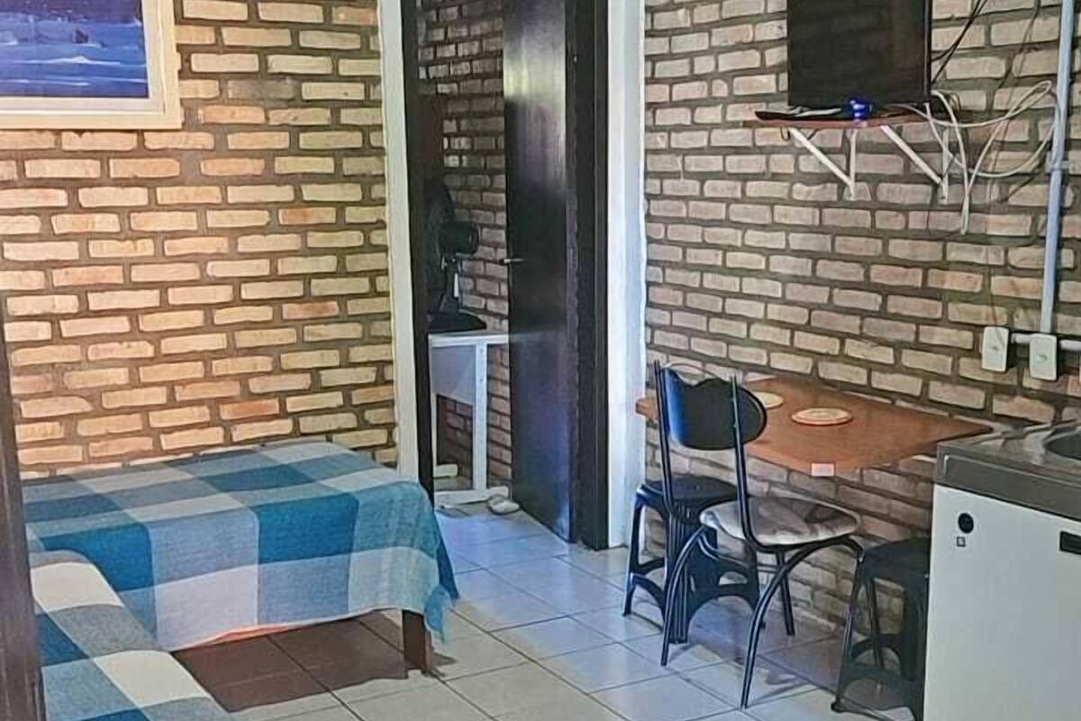 A room with two beds, a desk, a chair, a TV mounted on the wall, and a door leading to another room.
