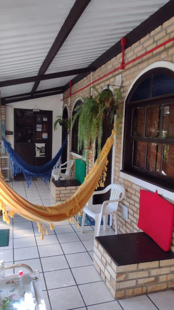 A covered outdoor area with a hammock, brick walls, and tiled flooring.