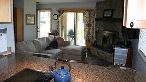 A cozy living room with a sofa, a blue kettle on the counter, and a stone fireplace. - Recently Renovated- Perfect for a Family Getaway! (Fraser)