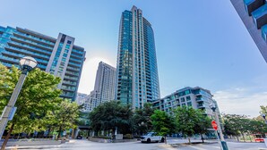 A modern urban street with tall buildings, a stop sign, and a bicycle in the foreground. - Elegant Downtown Oasis with City and Lake Views Plus Parking! (Old Toronto)