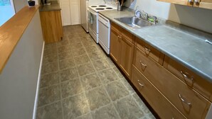 Une cuisine avec des meubles de rangement en bois, un four à micro-ondes, une cuisinière et un évier.