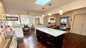 A modern kitchen with dark wood flooring, a central island, and pendant lighting. - Bloomington Indiana Rental- Entire House - 5 Bedrooms and 3 full bathrooms (Bloomington)