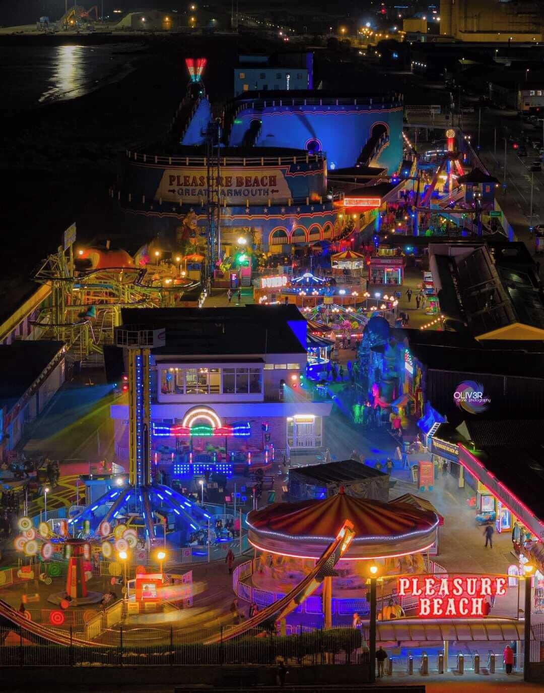 A nighttime view of Pleasure Beach with various amusement rides and attractions.