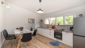 A modern kitchen with white cabinets, a stainless steel refrigerator, a dining table with chairs, and a blue rug on the floor. - Amazing home in Peracko Blato (Peracko Blato)