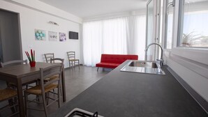 Eine moderne Küche mit Essbereich, einem roten Sofa und einem großen Fenster.