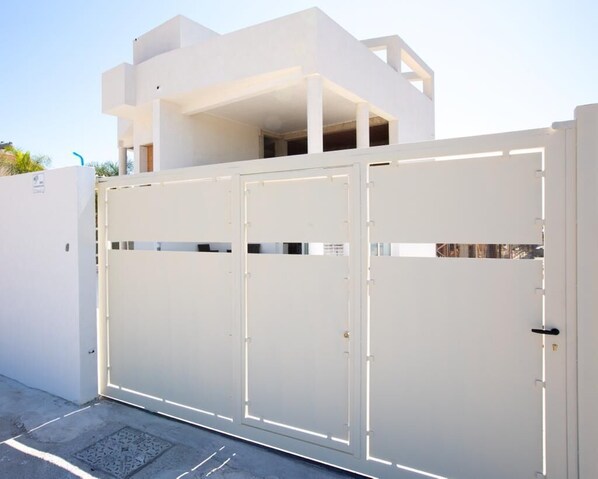 A modern white building with a gated entrance. - Modern and brand new apartment in villa five minutes from the sea and downtown (Avola. SR)