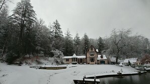 A two-story house with a snow-covered yard and a dock extending into a lake. - Magical Loft Apartment at Fernbrook Place (Otto)