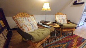 A cozy seating area with two wooden chairs, a small table, and a lamp. A colorful rug is on the floor. - Magical Loft Apartment at Fernbrook Place (Otto)