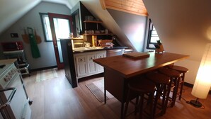 A kitchen with a central island, bar stools, a microwave, and a stove. - Magical Loft Apartment at Fernbrook Place (Otto)