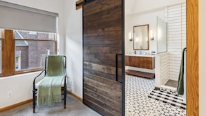 A modern bathroom with a wooden sliding door, a large mirror, and a checkered floor. - Over 4500 sqft of Luxury living [Billiards table, Arcade room, 5 BR & 4 BA] (Cleveland)