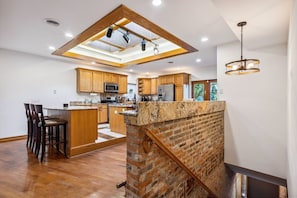 A modern kitchen with a central island, wooden cabinets, and a skylight. - Westside Warehouse-Hot Tub/GameRM/PoolTable & More (Cleveland)