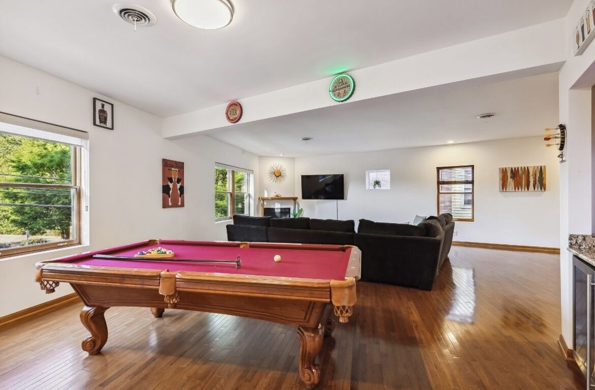 A spacious room with a pool table, a sofa, and a television.