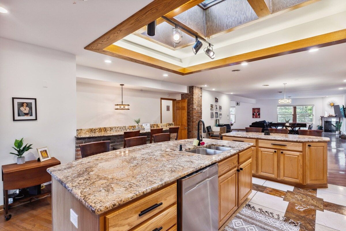 A spacious kitchen with a central island, wooden cabinets, and a modern pendant light.