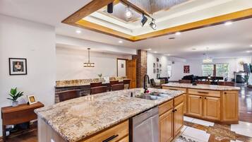 A spacious kitchen with a central island, wooden cabinets, and a modern pendant light.