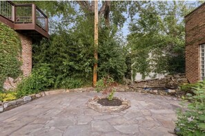 Stroll through this serene courtyard surrounded by a brick wall and a wooden fence, featuring a charming planter and a staircase leading to a balcony.