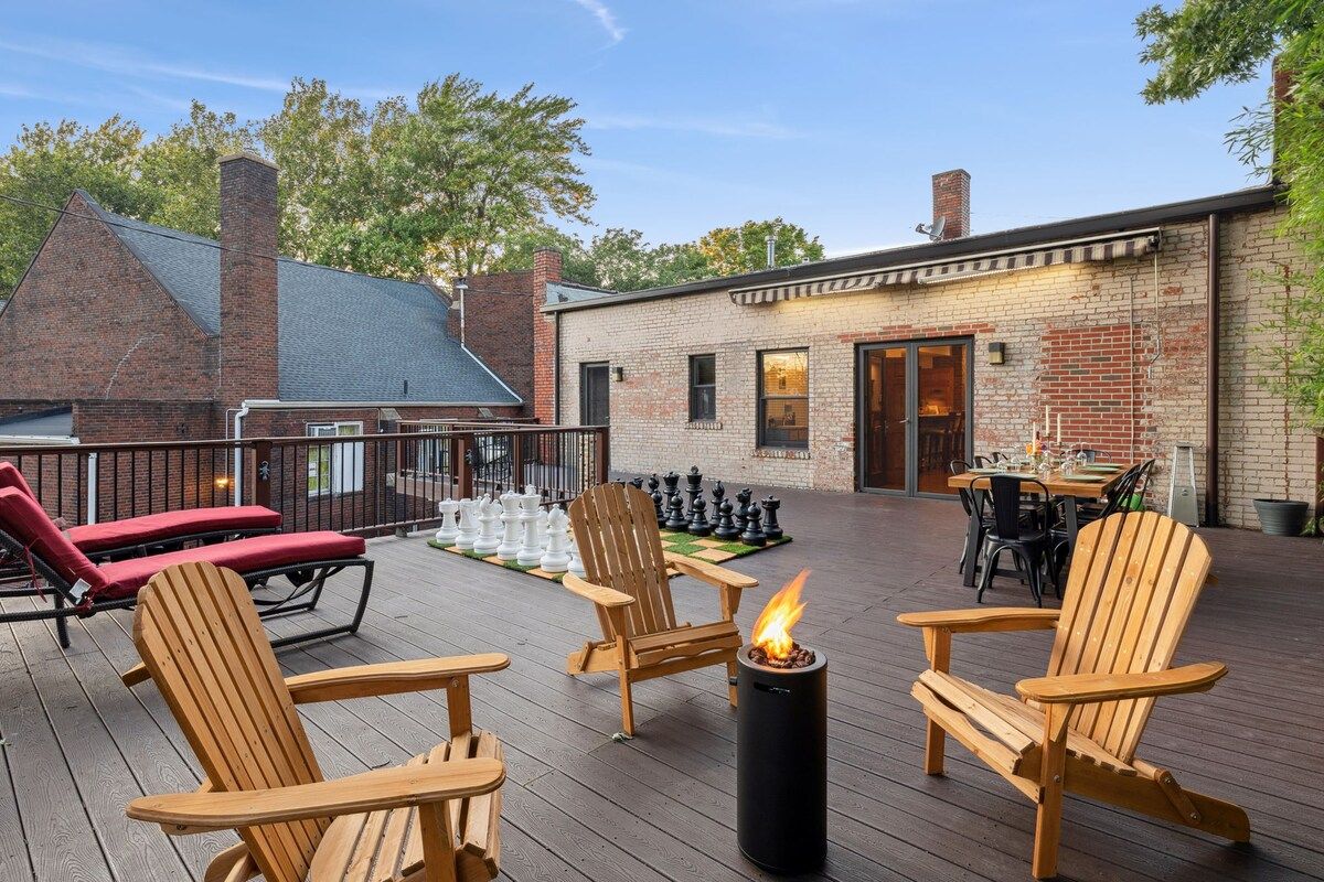Eine Terrasse mit Adirondack-Stühlen, einer Feuerstelle und einem Schachbrett.